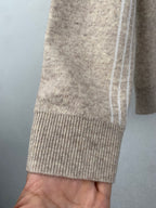 Ribbed cuff and hem on beige knit sweater with subtle monogram texture