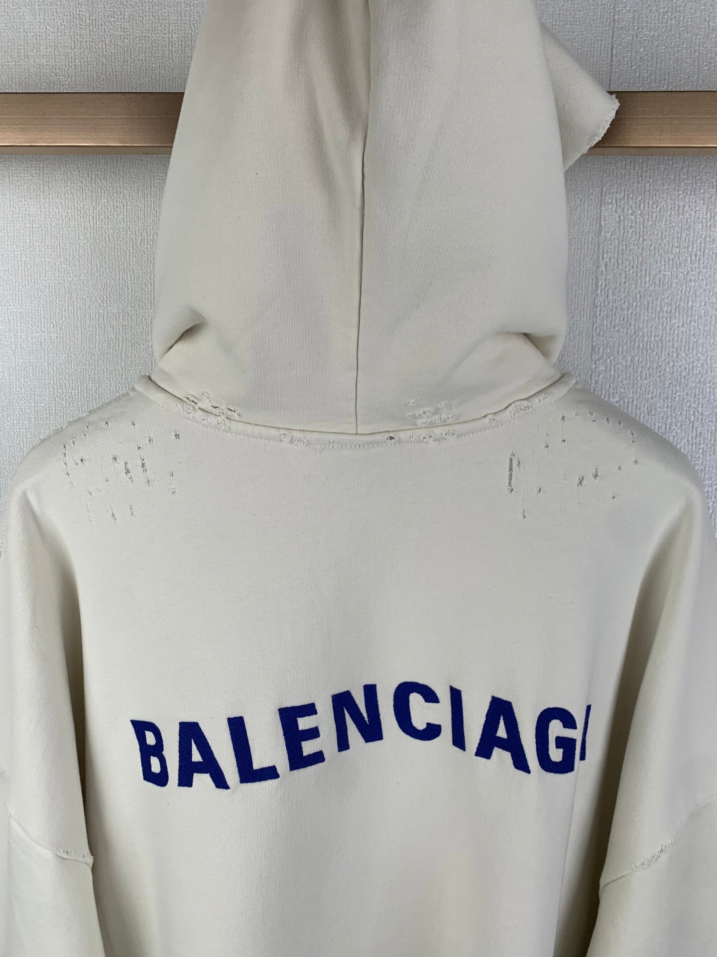 Cream hoodie back hood area with blue BALENCIAG lettering