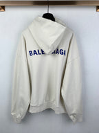 Cream zip-up hoodie with hood, back view, and blue BALENCIAGA logo