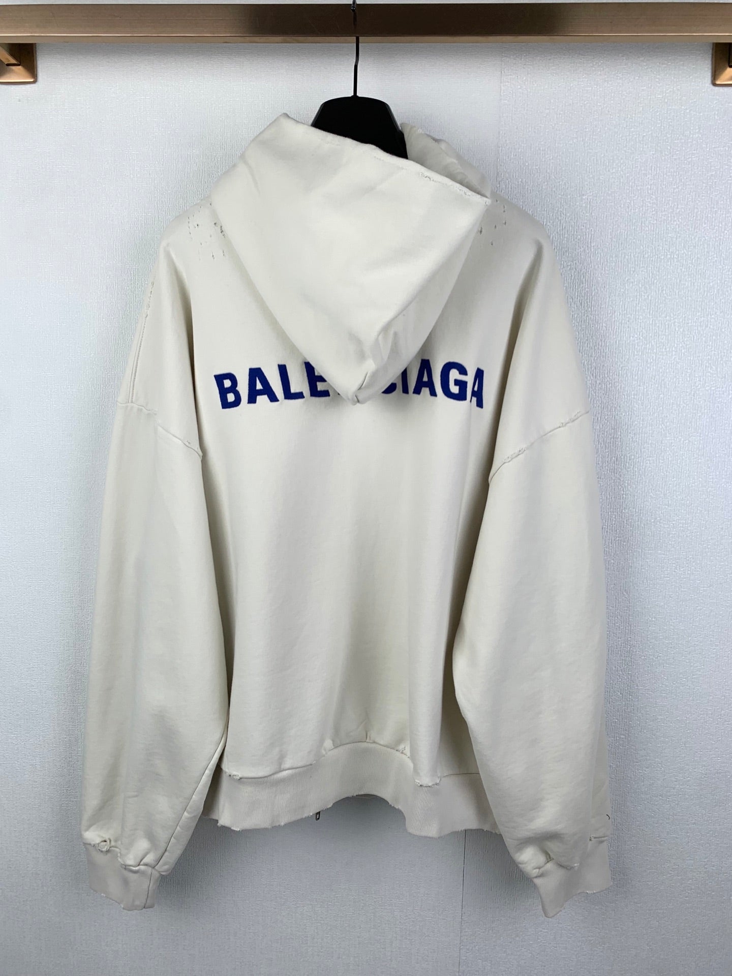 Cream zip-up hoodie with hood, back view, and blue BALENCIAGA logo