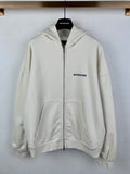 Cream zip-up hoodie with hood, front pockets, and blue BALENCIAGA chest logo
