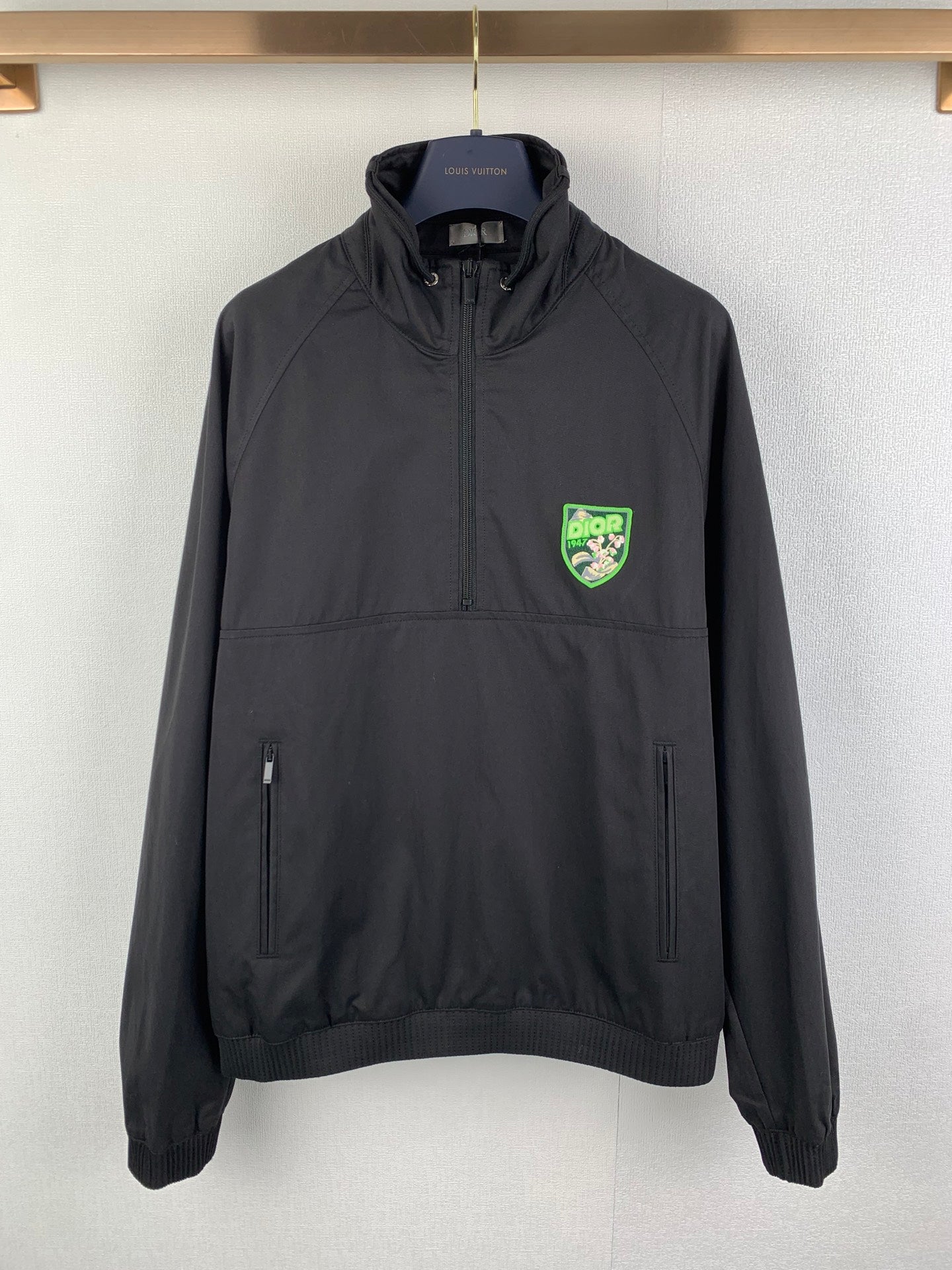 Black Dior zip-up jacket with stand collar, two front pockets, and logo patch