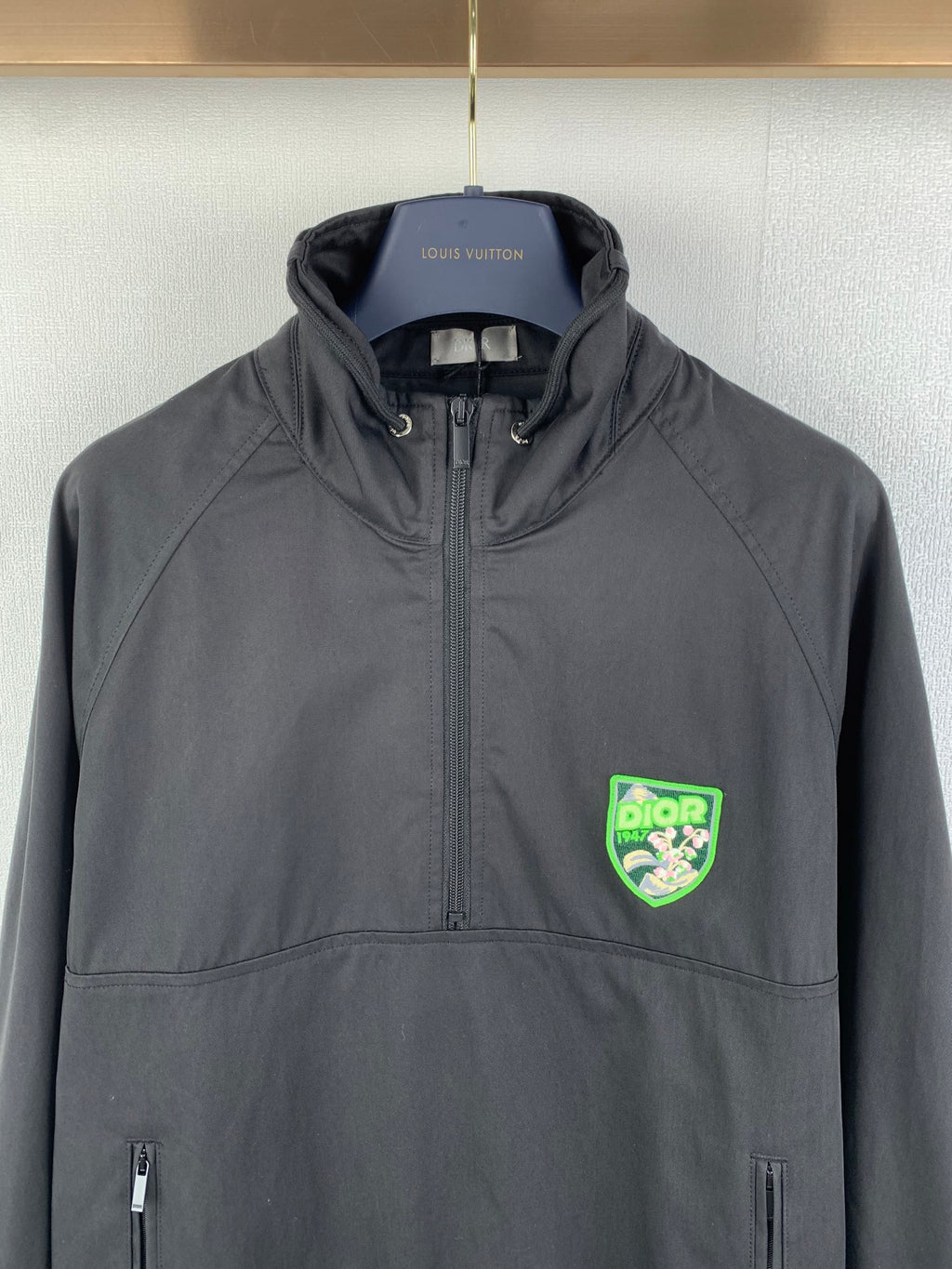 Dark gray Dior zip-up jacket with stand collar, front pockets, and green logo patch