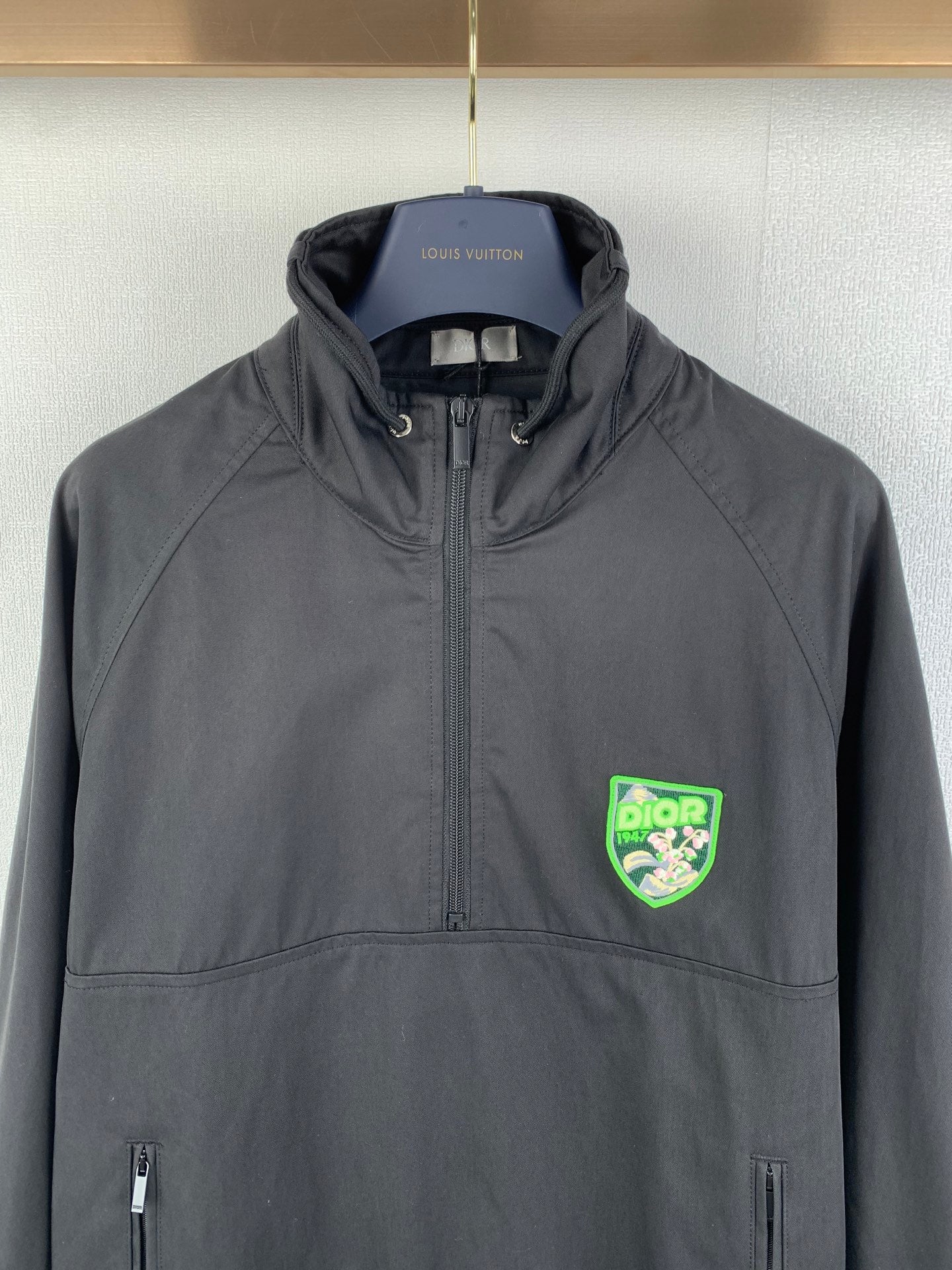 Dark gray Dior zip-up jacket with stand collar, front pockets, and green logo patch