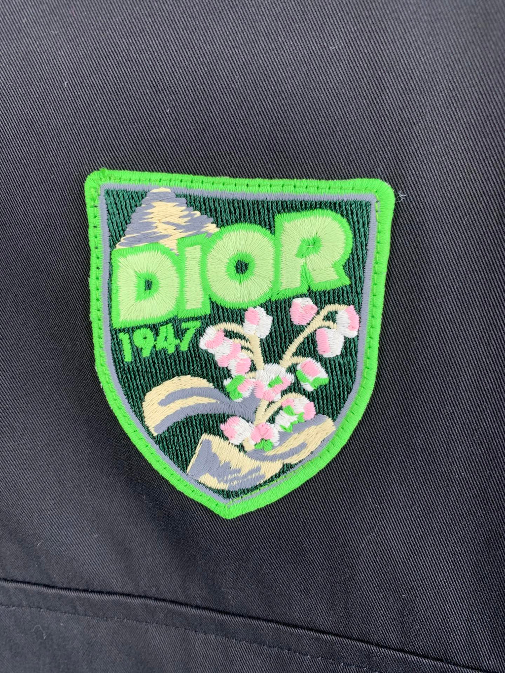 Green-and-black Dior logo patch on a dark gray jacket front