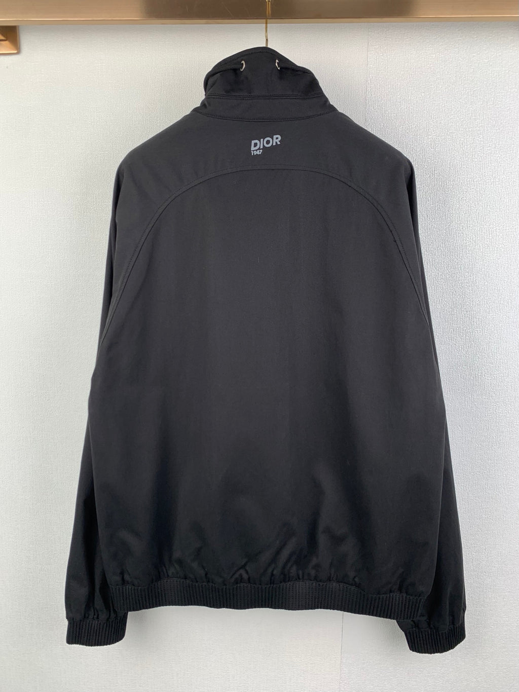 Back view of black Dior jacket with stand collar and small logo at upper back