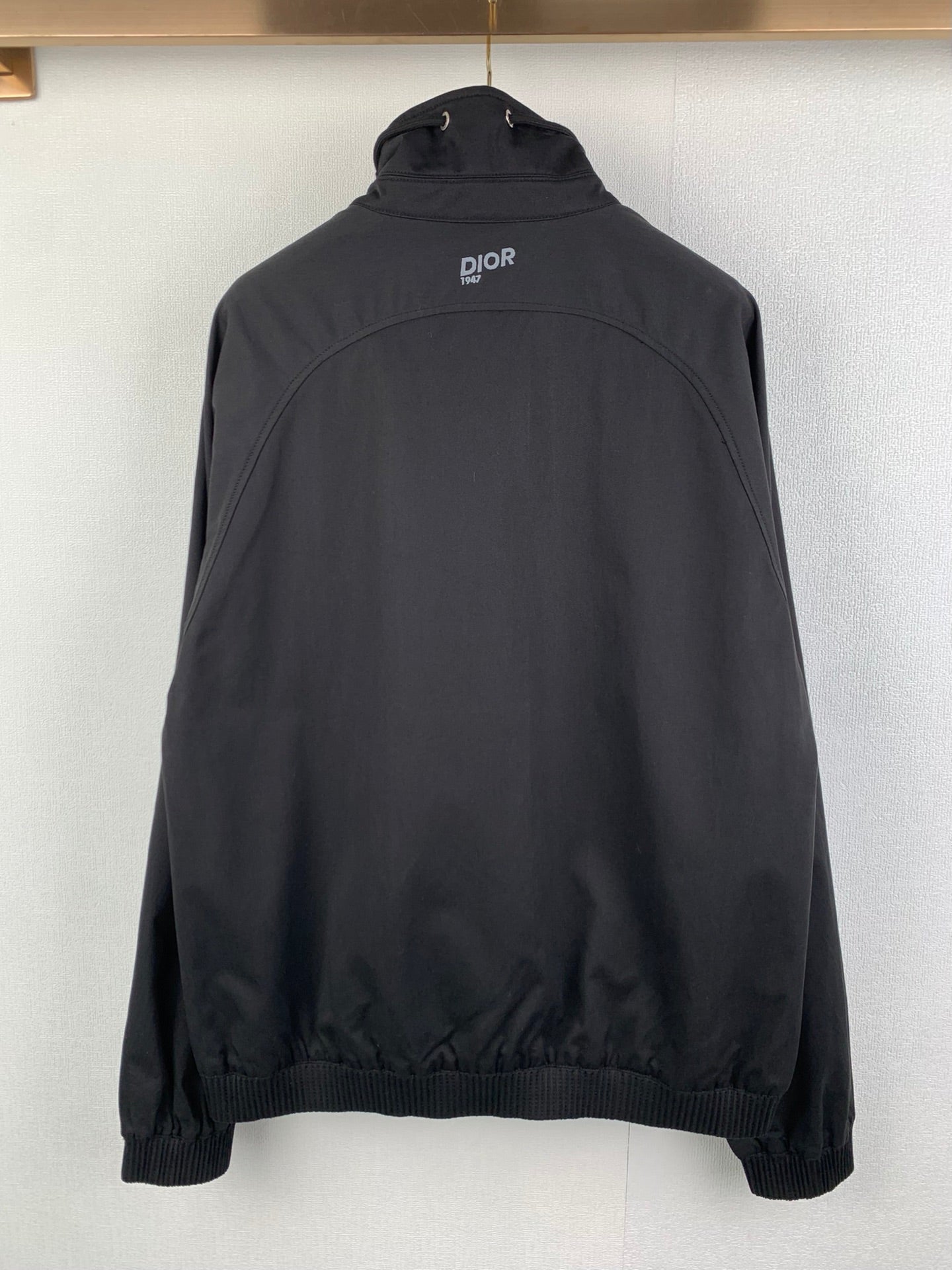 Back view of black Dior jacket with stand collar and small logo at upper back
