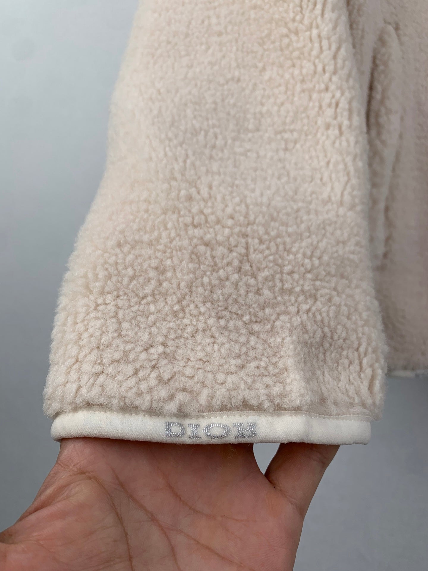 Cream sherpa long coat cuff and hem with embroidered logo tag