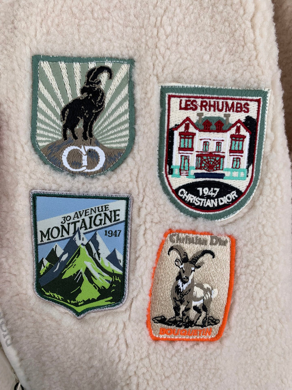 Ivory sherpa jacket front close-up with embroidered crest patches