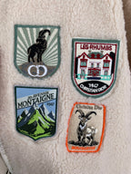 Ivory sherpa jacket front close-up with embroidered crest patches