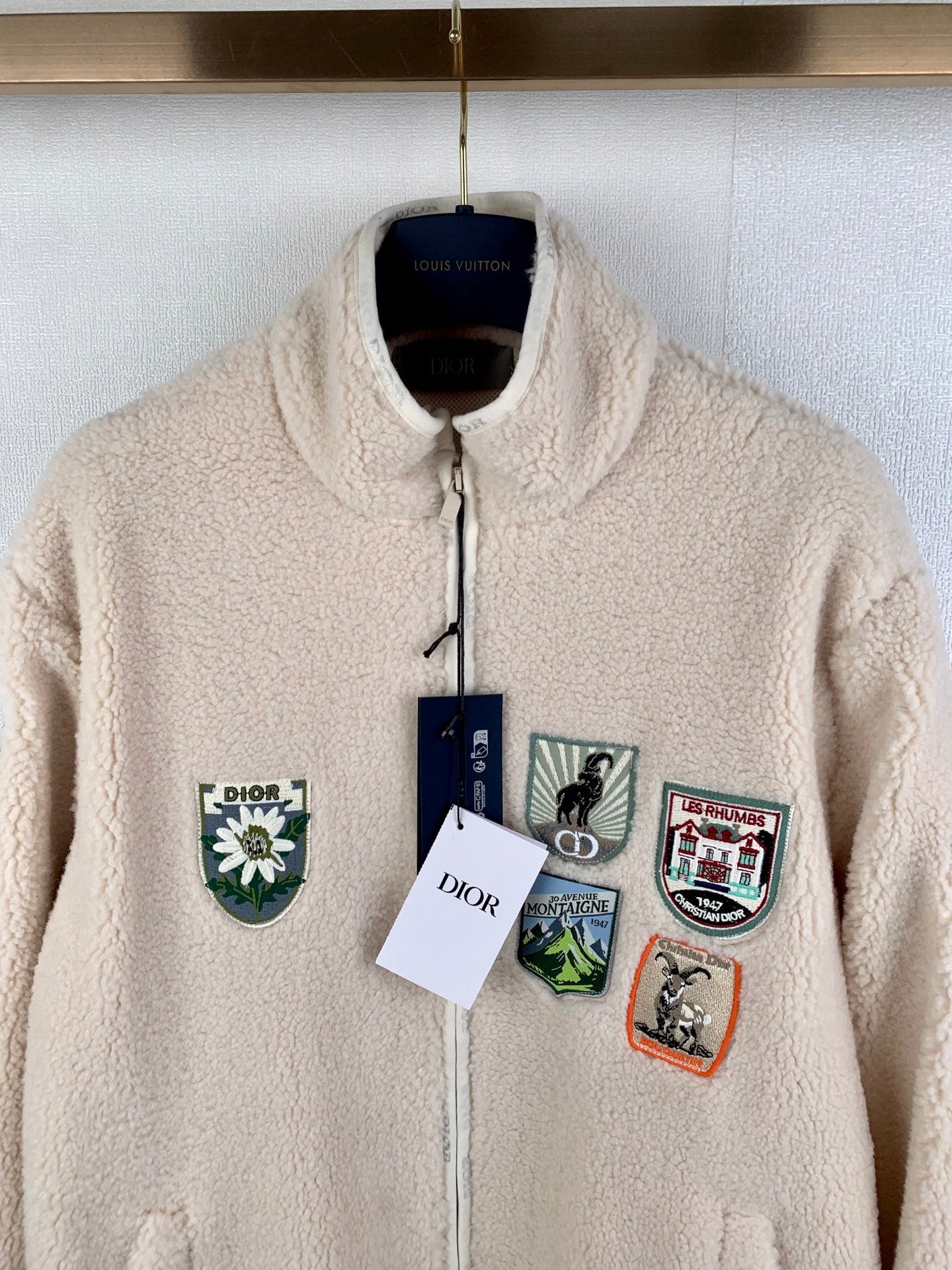 Cream sherpa zip-up jacket with stand collar and multiple front embroidered patches