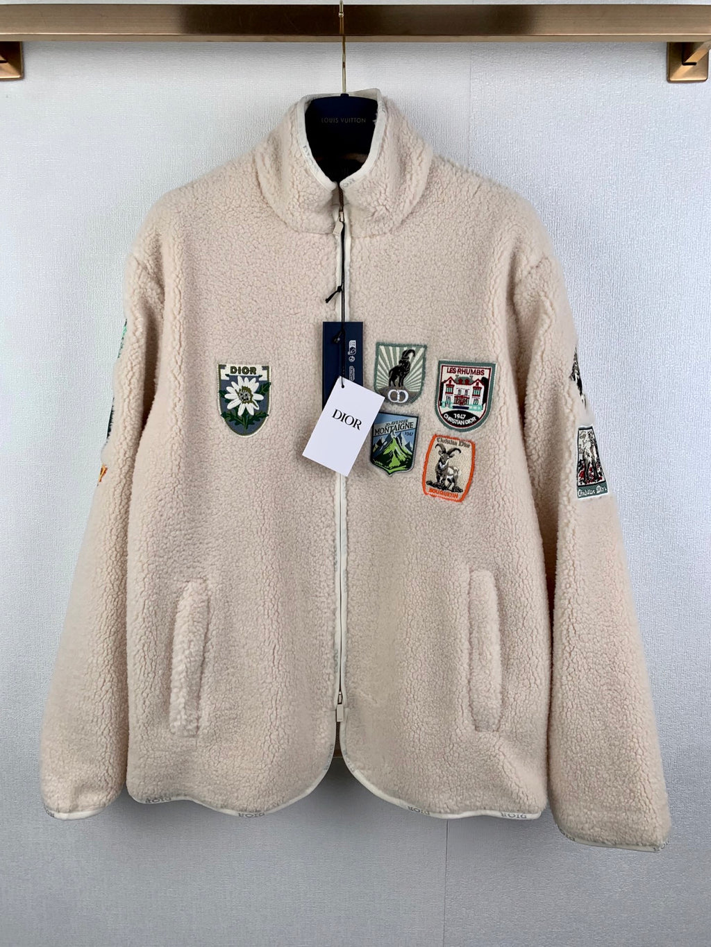 Ivory sherpa zip-up jacket with front pockets and colorful embroidered patches