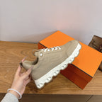 Beige lace-up sneakers with thick white sole, held up for front detail.