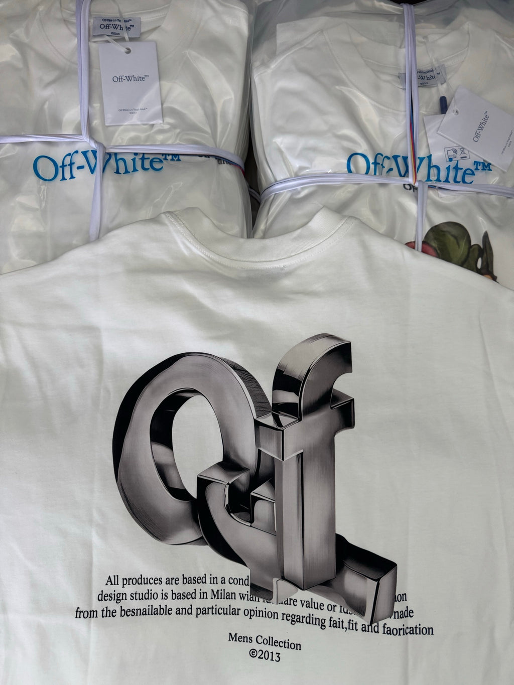 Off-white T-shirt with oversized metallic 3D logo and small paragraph text