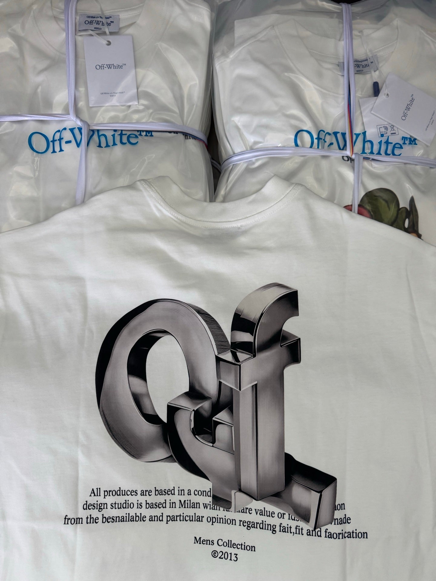 Off-white T-shirt with oversized metallic 3D logo and small paragraph text