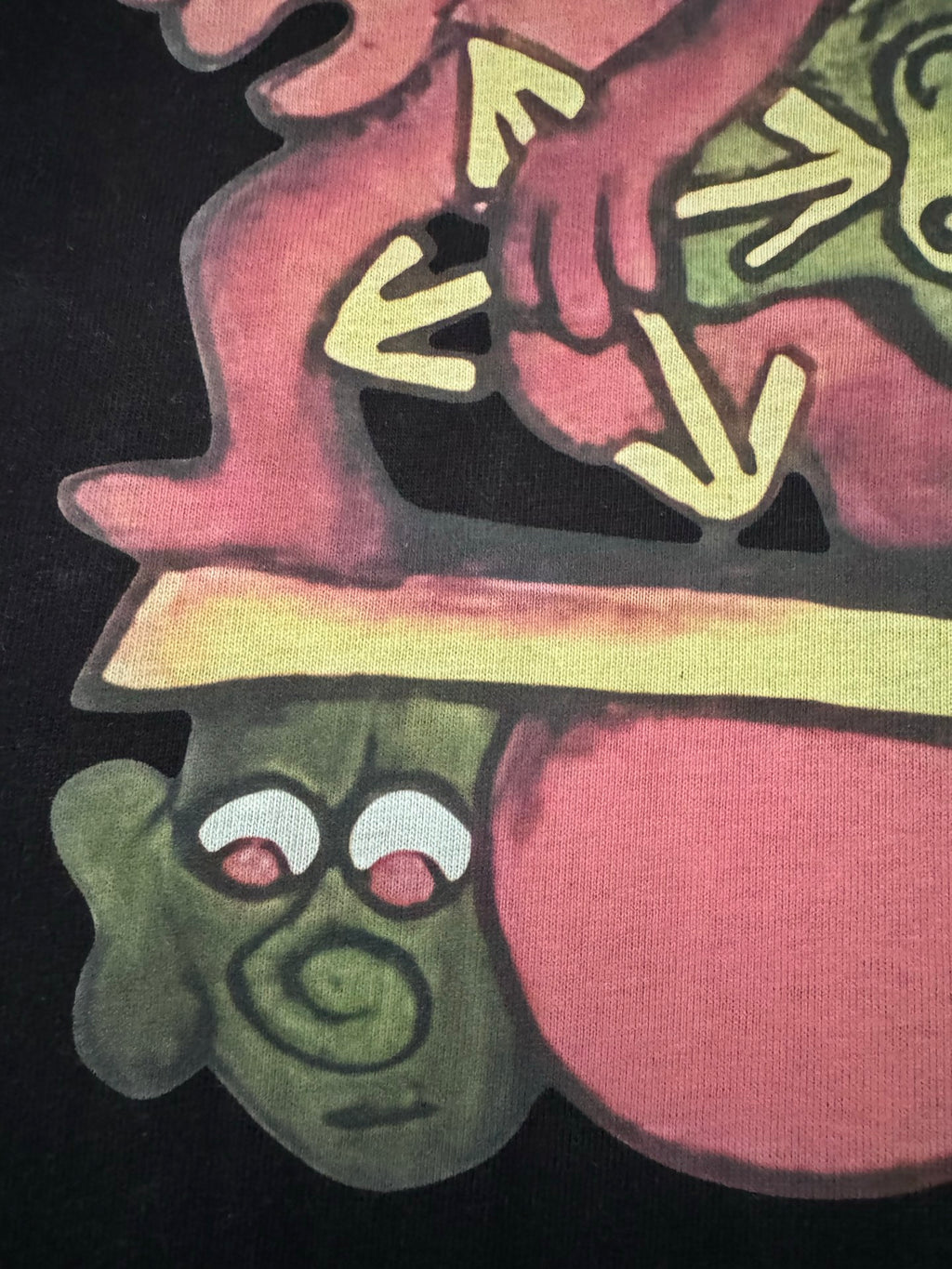 Black T-shirt with colorful cartoon character and shoe graphic, close-up