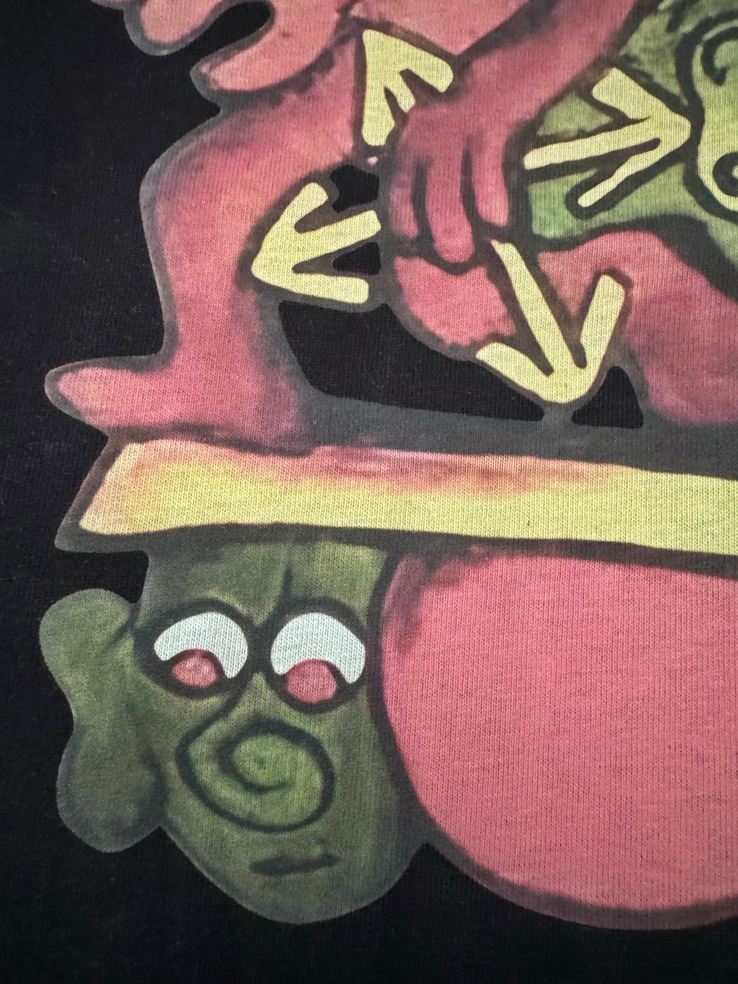 Black T-shirt with colorful cartoon character and shoe graphic, close-up