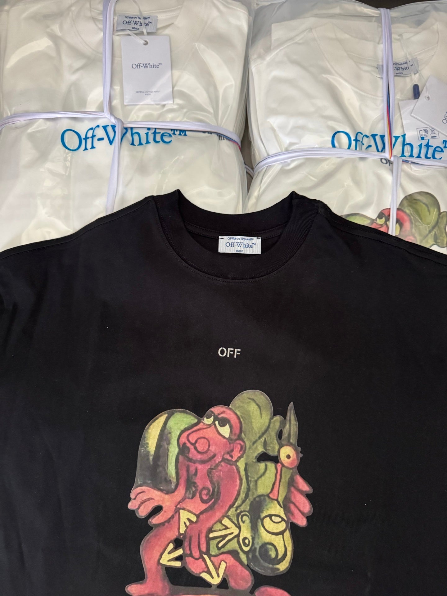Black T-shirt with crew neck, small OFF text, and colorful cartoon graphic