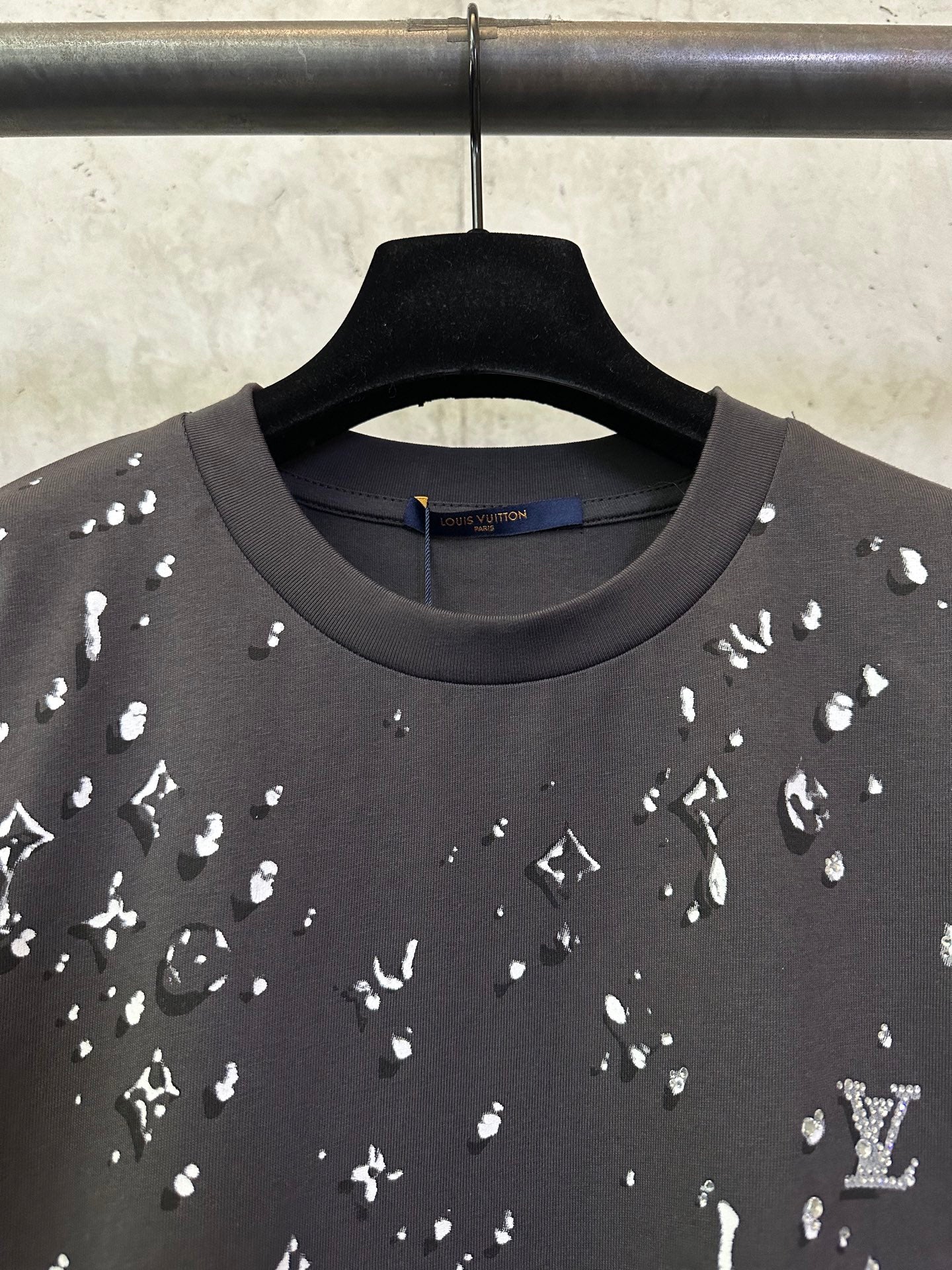 Black crewneck T-shirt with scattered white motif print, neckline close-up
