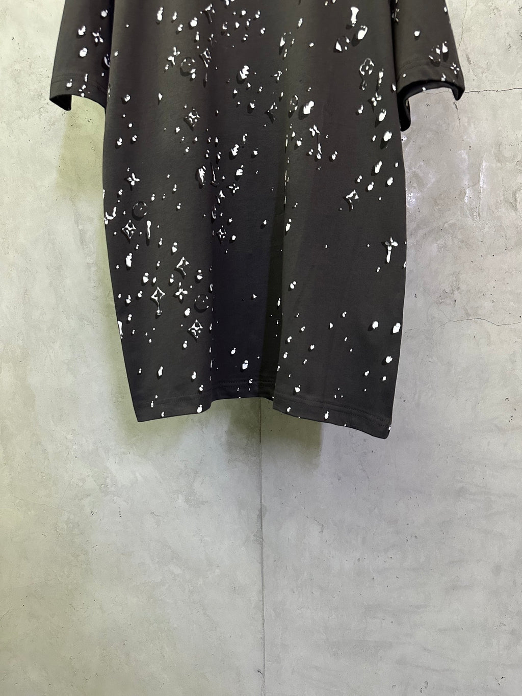Black short-sleeve T-shirt with scattered white motif print, front lower view