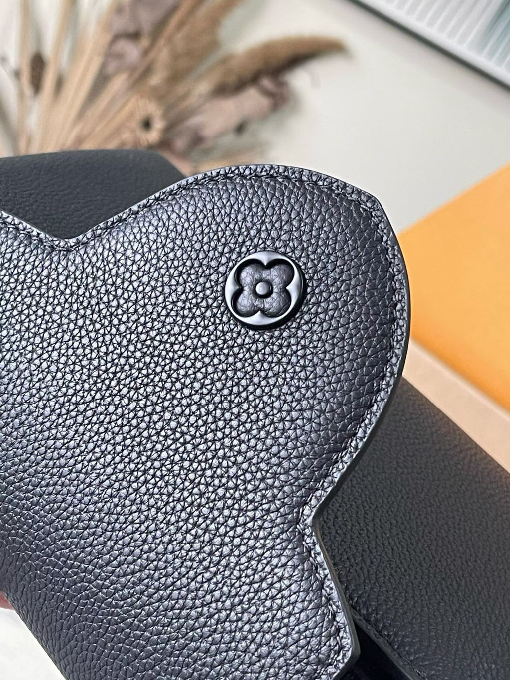 Navy leather bag front with circular emblem and textured grain finish