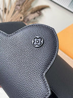 Navy leather bag front with circular emblem and textured grain finish