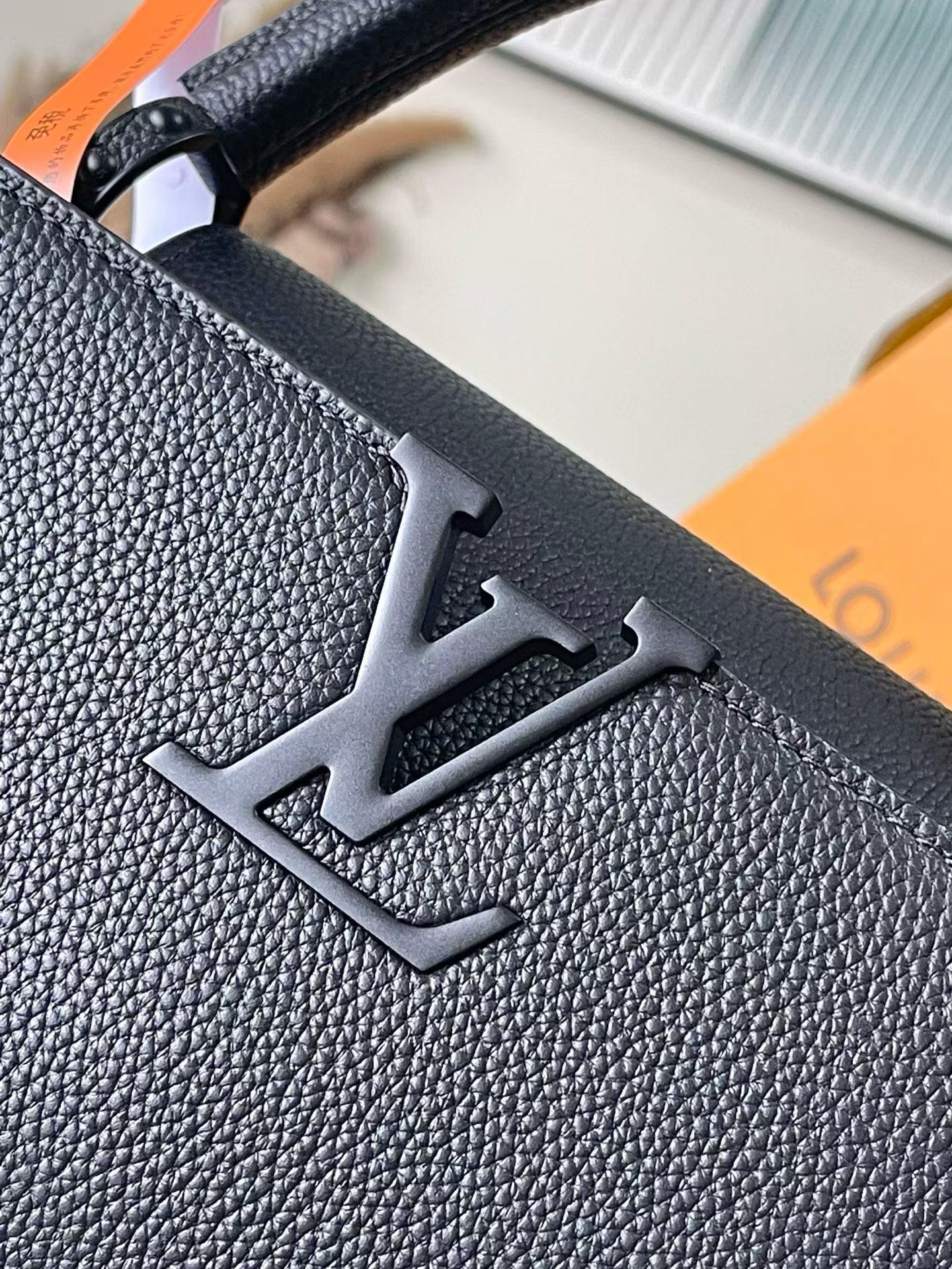 Close-up of Louis Vuitton LV monogram on textured navy leather