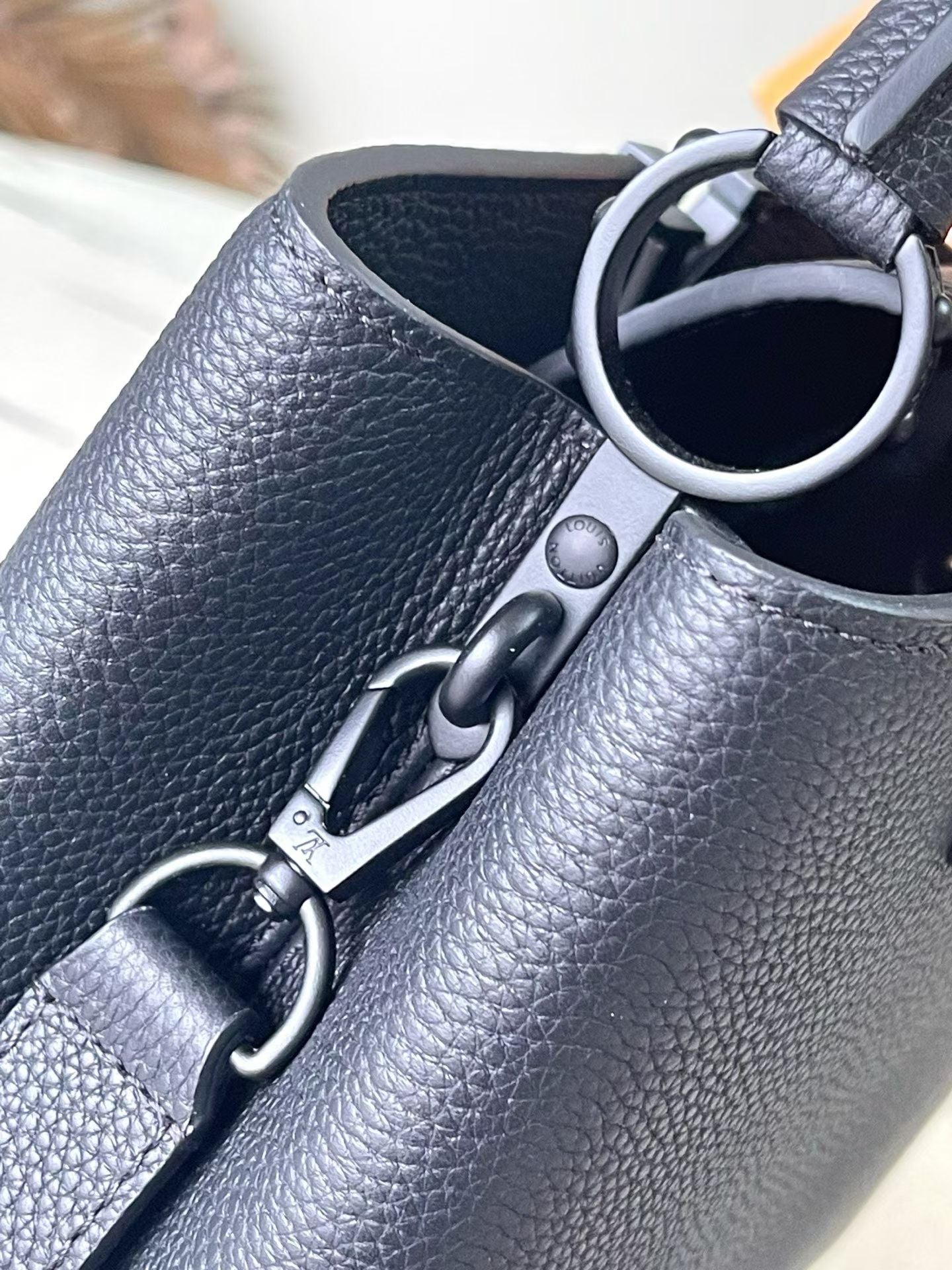 Dark leather handbag with metal strap hardware and ring attachment