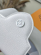 Louis Vuitton clover emblem on white textured leather flap