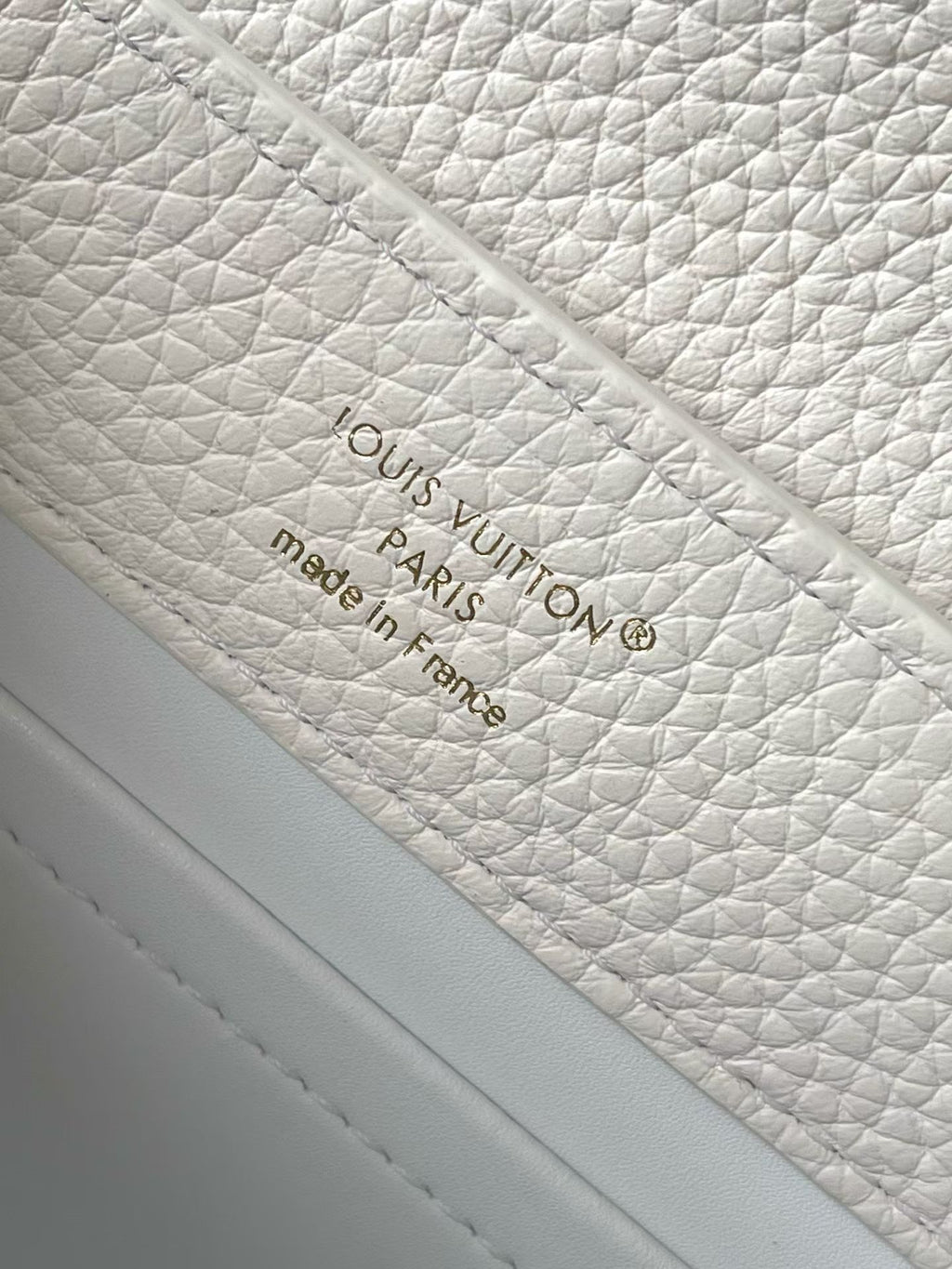 White leather handbag interior with embossed Louis Vuitton label made in France