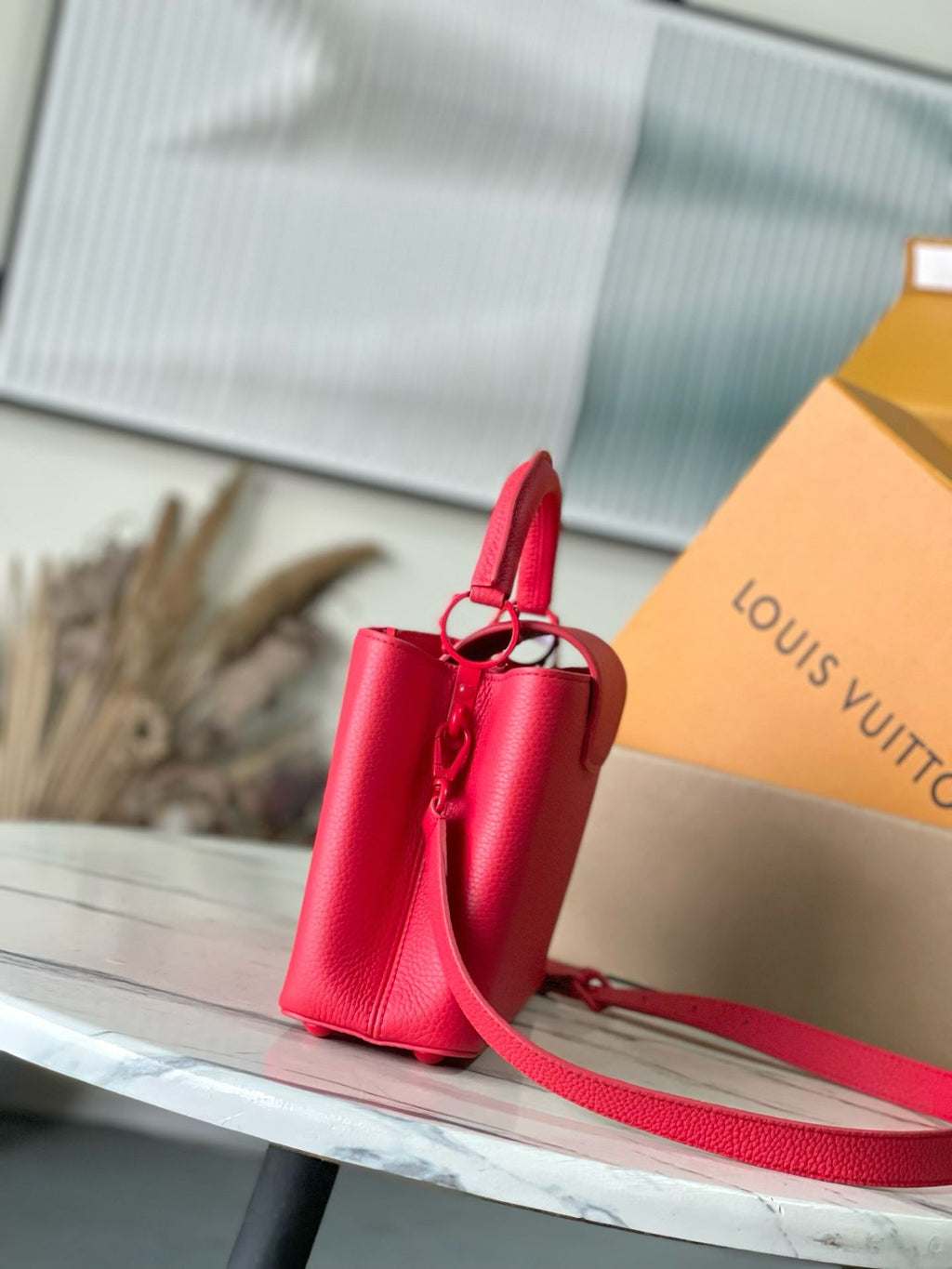 Red Louis Vuitton handbag with front flap and crossbody strap, side view