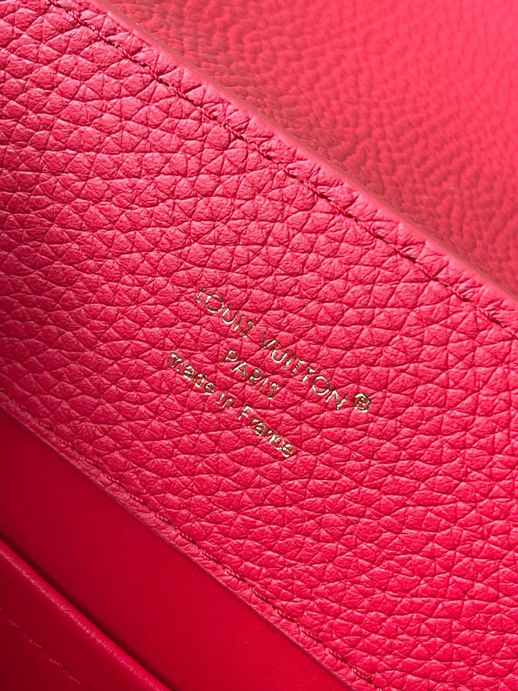 Red leather handbag with stamped Louis Vuitton text on interior panel