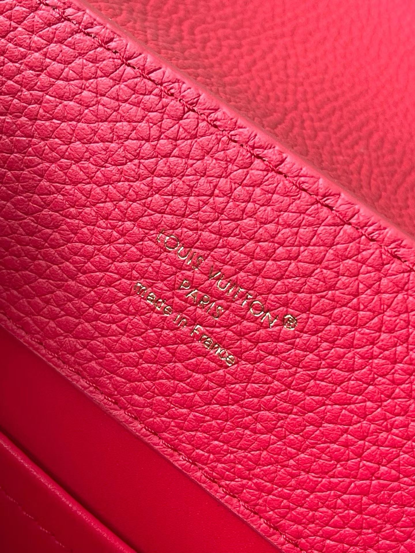 Red leather handbag with stamped Louis Vuitton text on interior panel