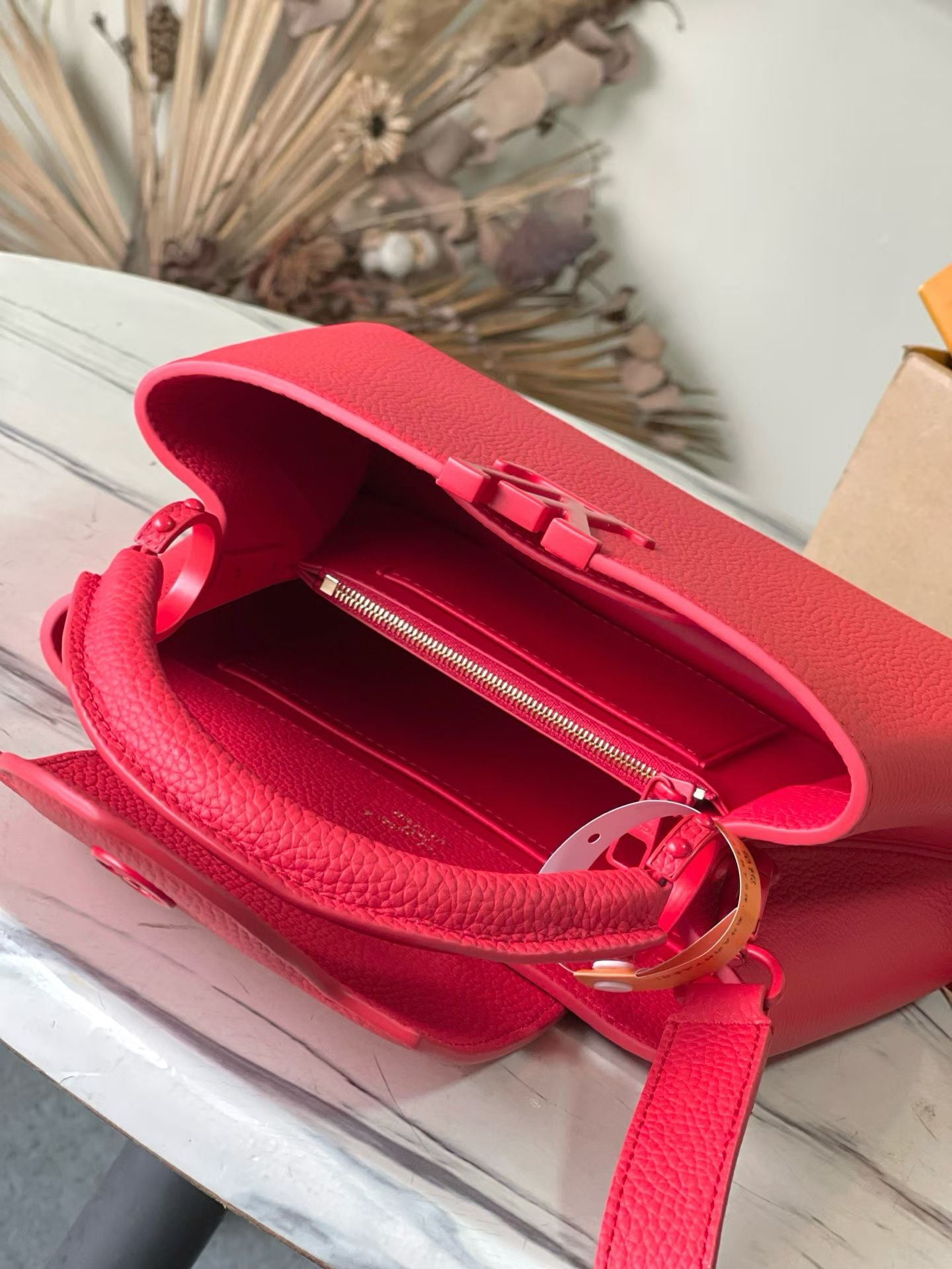 Red leather handbag open to show zipper pocket, Louis Vuitton interior