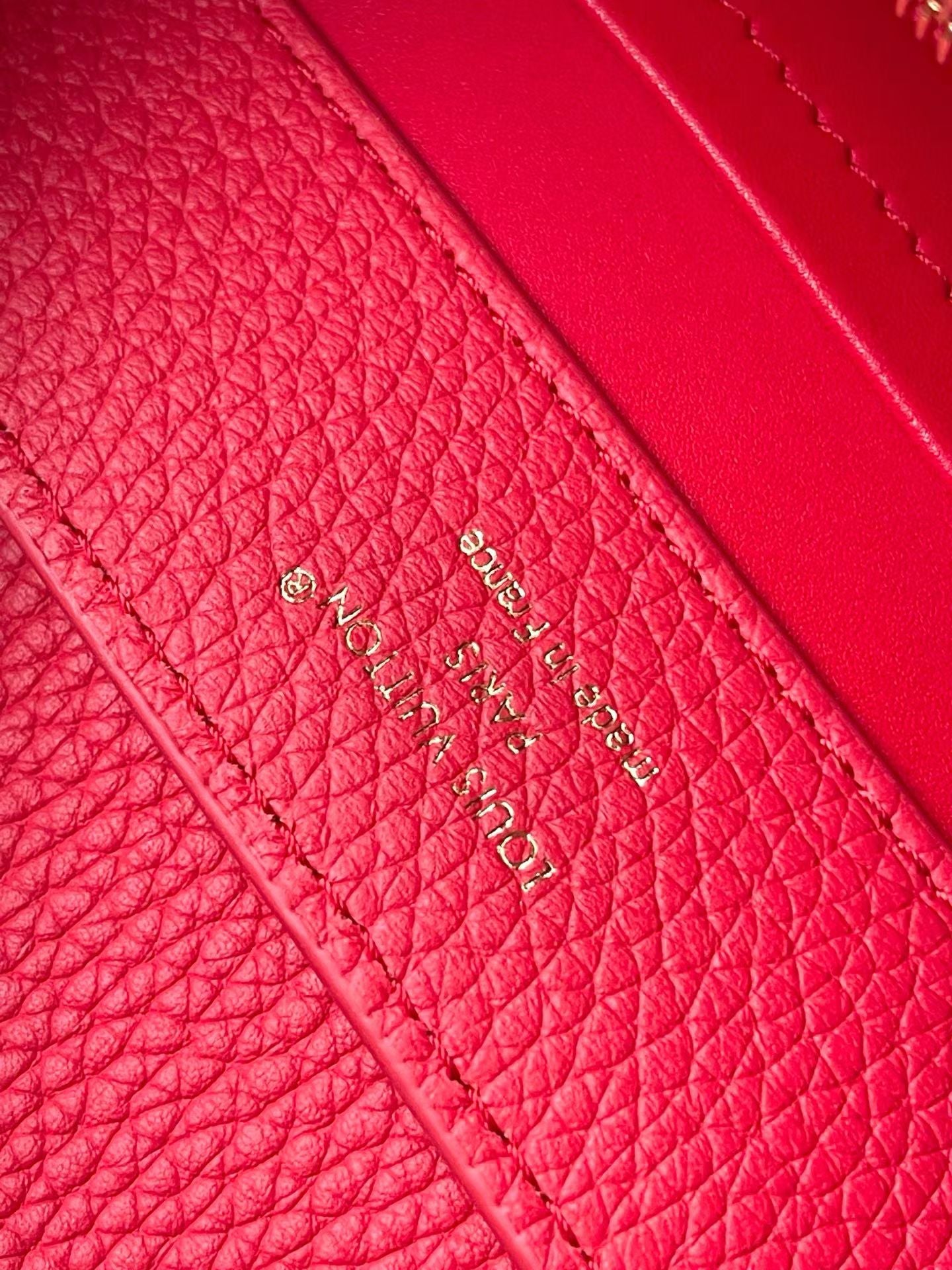 Red leather handbag side panel with gold-embossed logo text