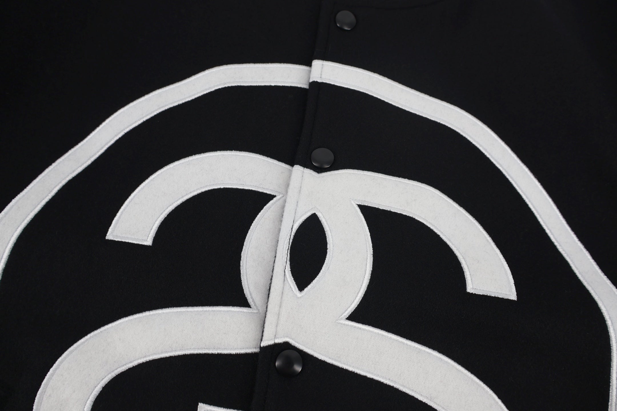 Black jacket chest panel with white outlined logo detail