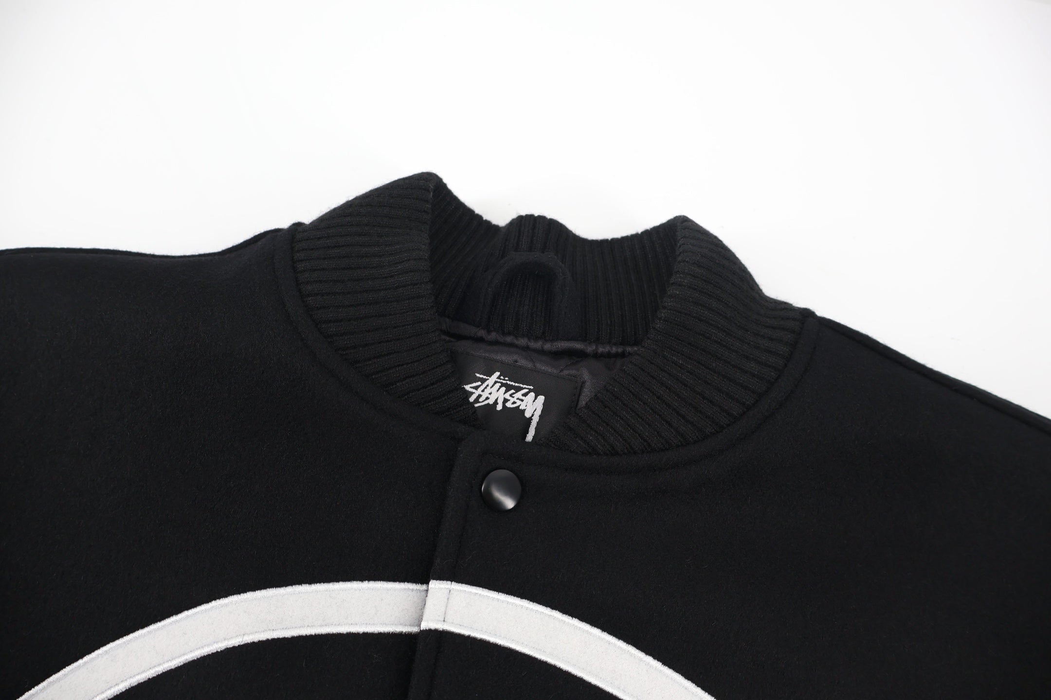 Black ribbed knit collar with snap placket and Stussy logo