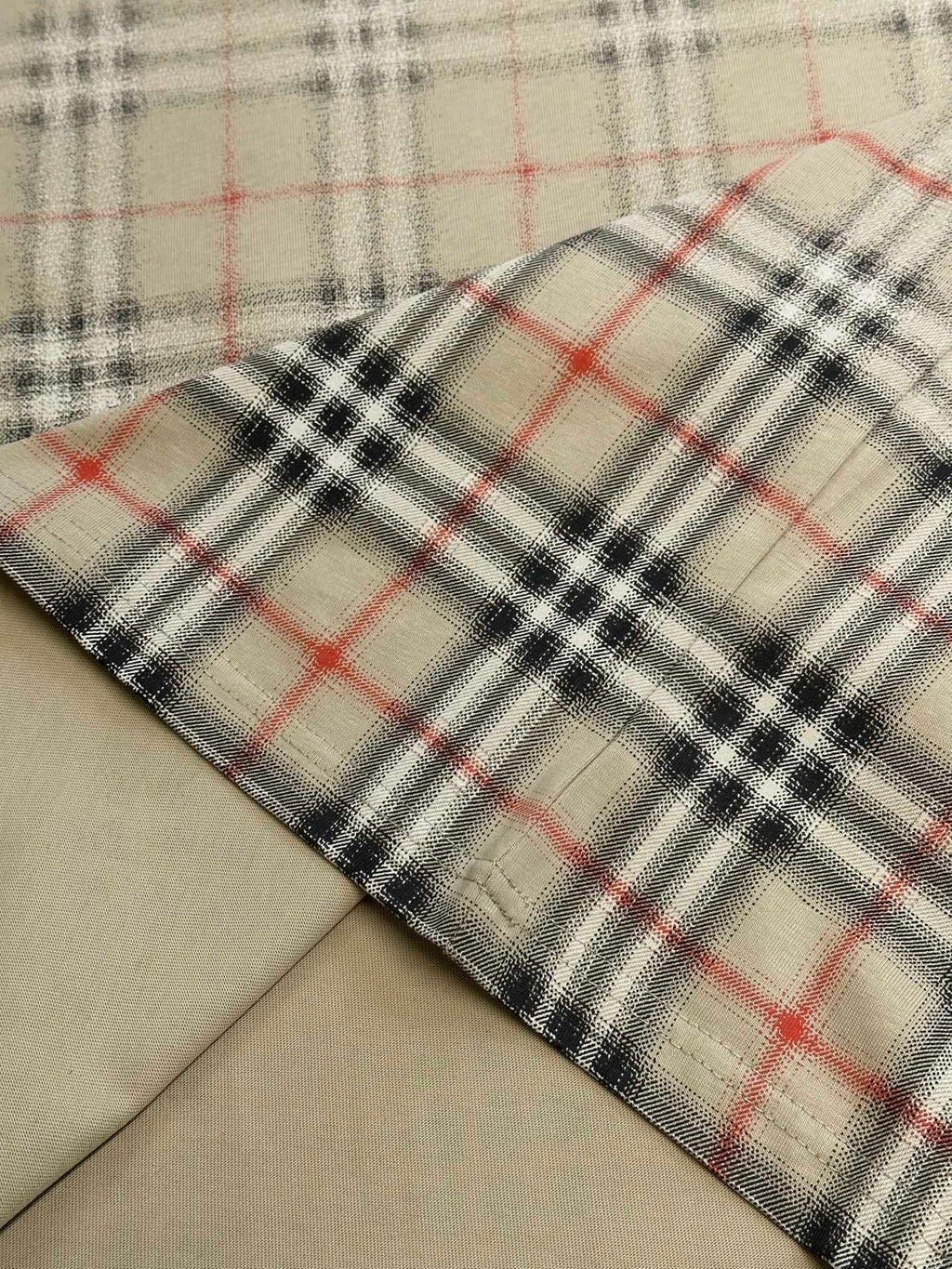 Close-up of beige fabric with red and dark check plaid hem edge