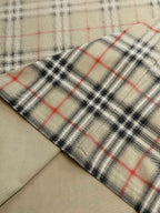 Close-up of beige fabric with red and dark check plaid hem edge