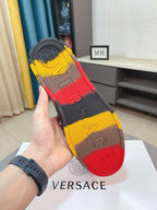 Luxury Versace sneaker outsole close-up, gray tread with red and yellow logo panels