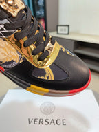 Luxury Versace sneaker close-up, black leather with gold trim, textured laces, red-yellow sole