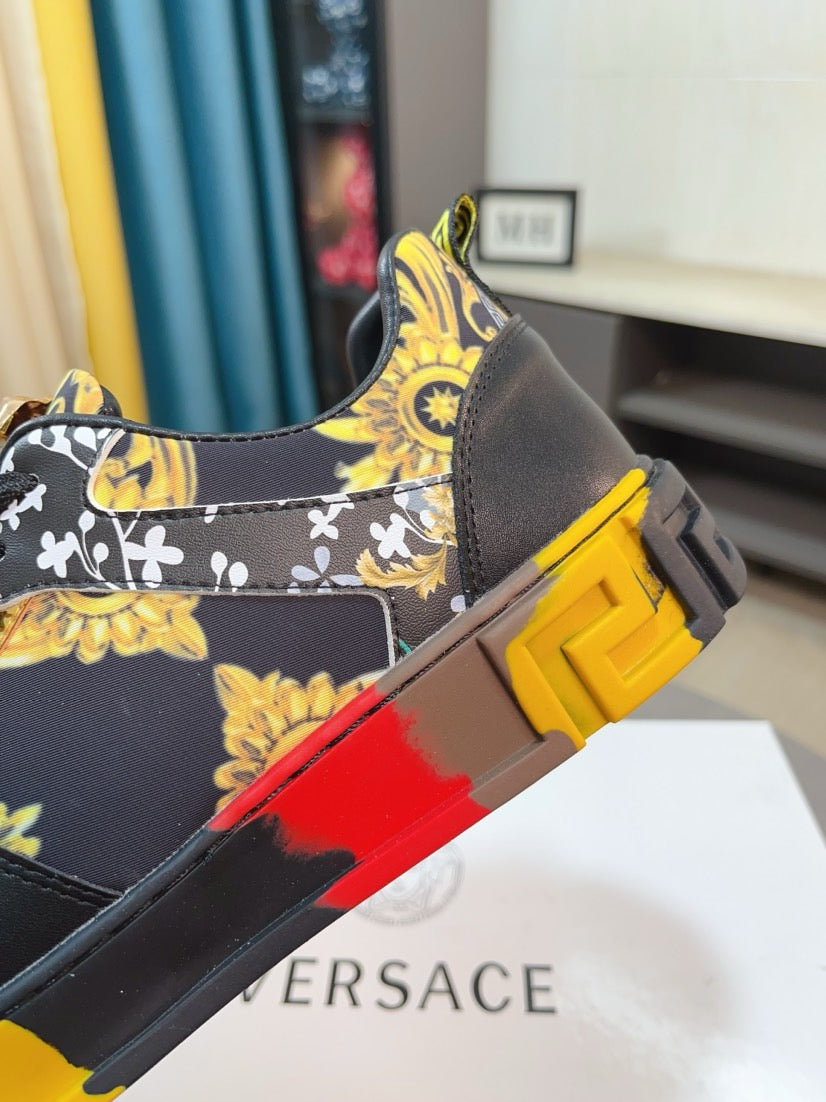 Luxury Versace sneaker side view, black with gold pattern fabric and chunky yellow-red sole