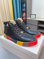 Pair of black high-top sneakers on box; lace-up with gold decorative charms and red/yellow sole