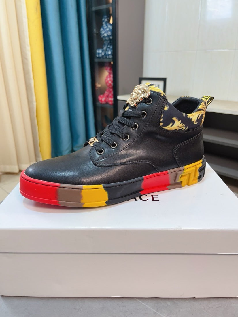 Black high-top sneaker with lace-up front and gold ornament at side; red and yellow sole