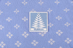 Close-up of a light blue fabric label with logo on a repeating white pattern shirt