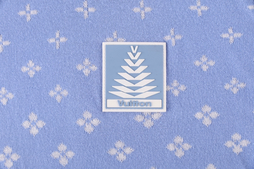 Close-up of a light blue fabric label with logo on a repeating white pattern shirt