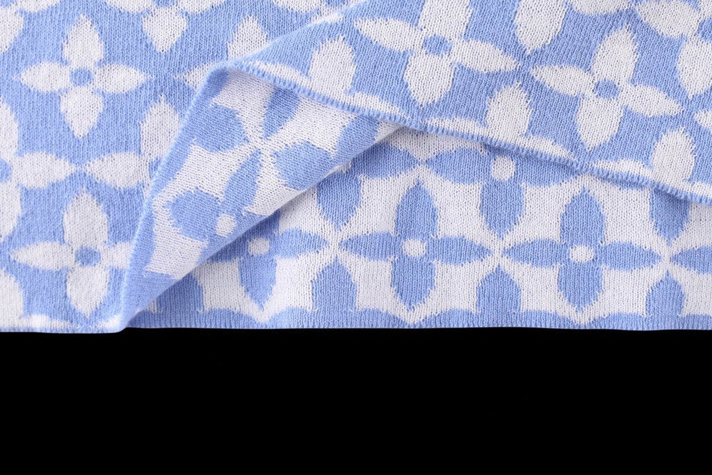 Light blue fabric with repeating white pattern and folded sleeve cuff detail