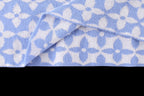 Light blue fabric with repeating white pattern and folded sleeve cuff detail