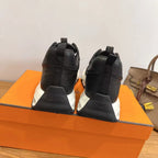 Black unisex sneakers with 'Hermes' on heel tab, white laces, chunky white soles.