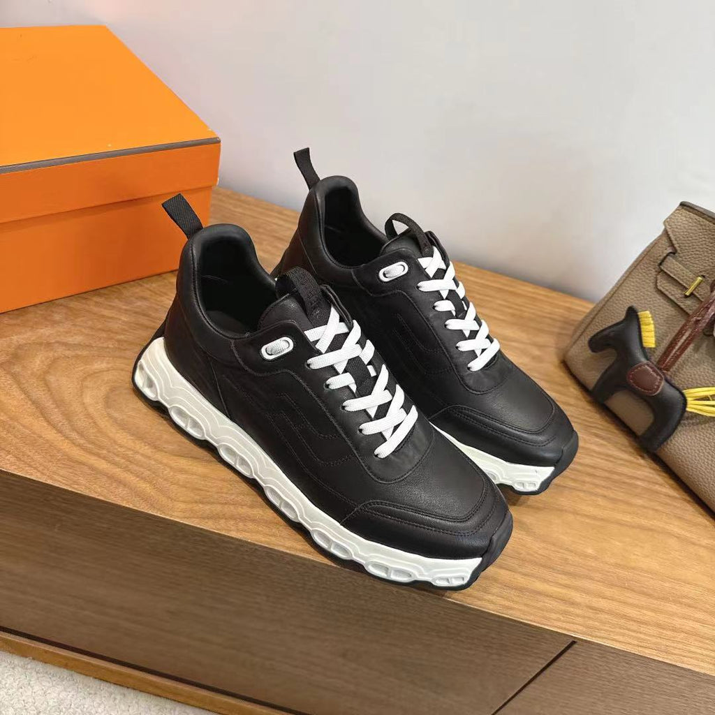 Pair of black unisex sneakers with white laces and chunky white soles.